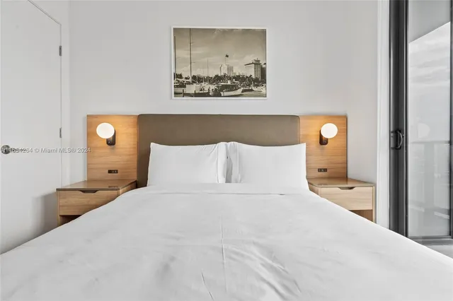 a bedroom with a bed and a lamp on dresser