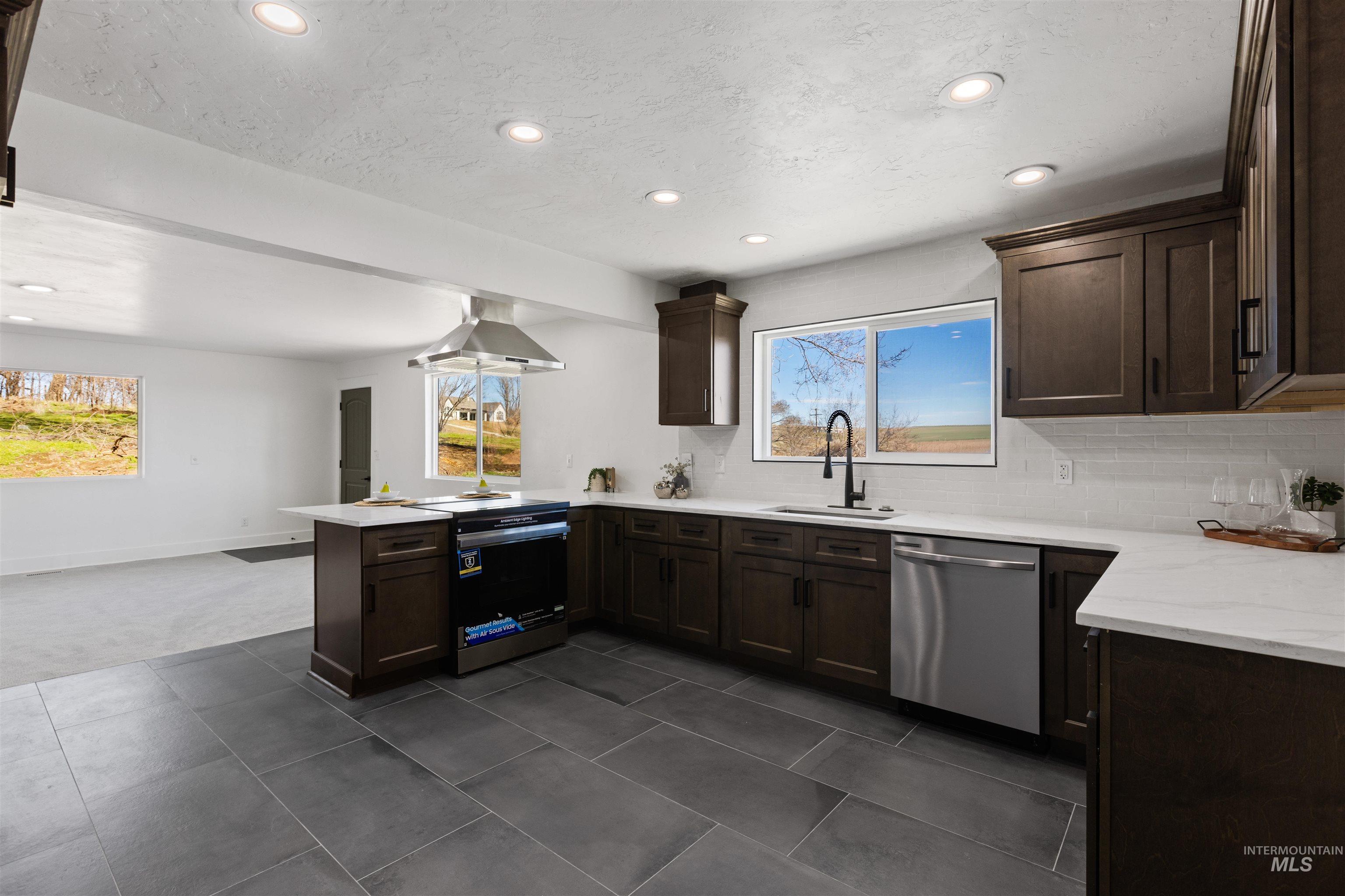 29862 Emmett Road Caldwell, ID 83607 - Photo 35 of 44 Kitchen with dark wood finish cabinets, a peninsula, decorative backsplash, stainless steel appliances, and recessed lighting