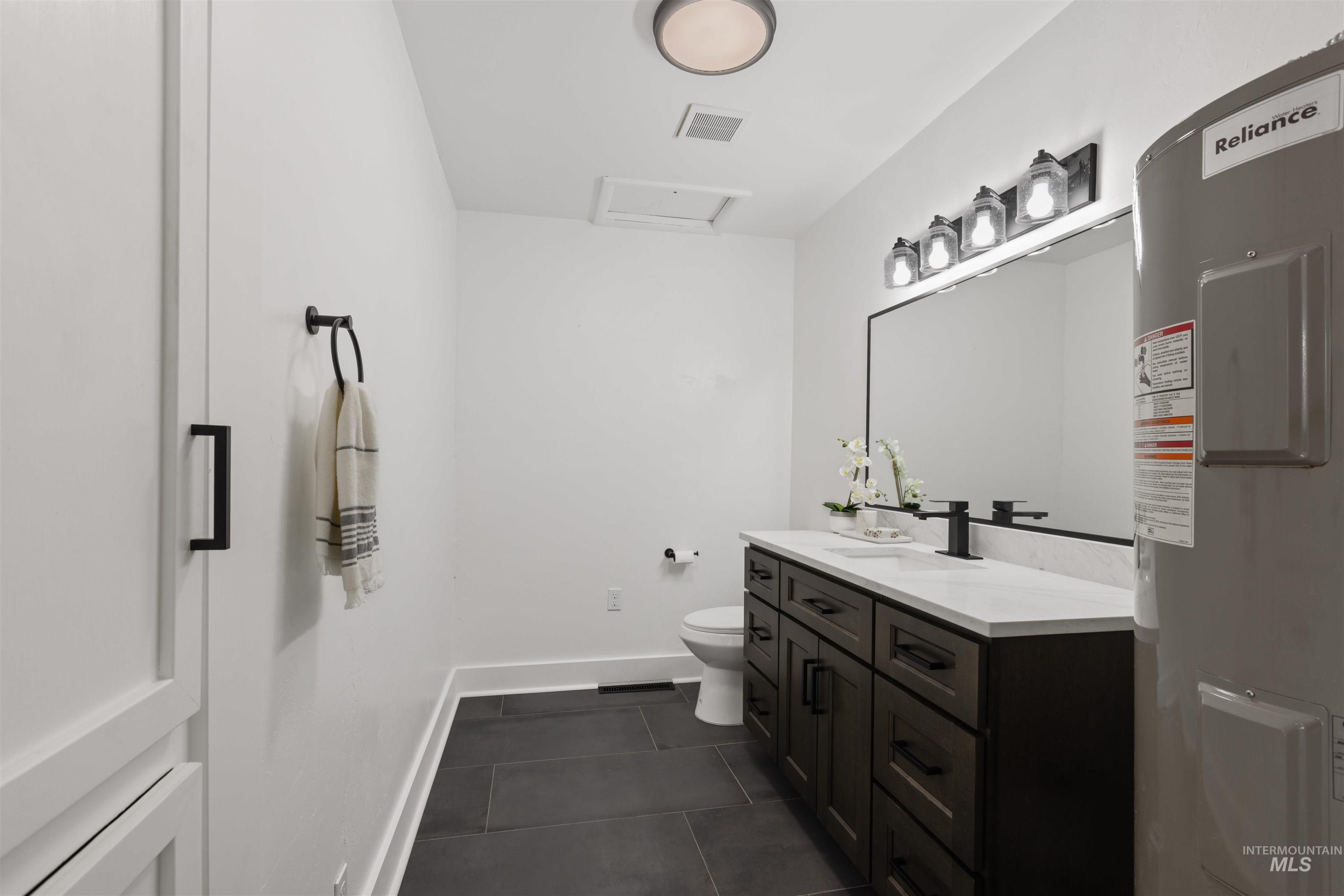 29862 Emmett Road Caldwell, ID 83607 - Photo 37 of 44 Half bath featuring electric water heater, vanity, and dark tile patterned floors