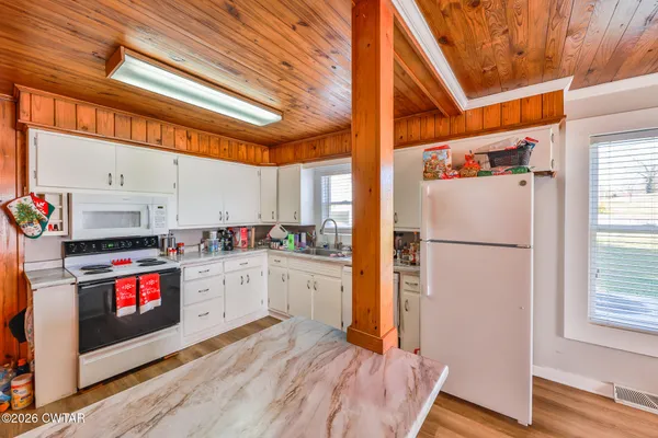 a kitchen with stainless steel appliances a refrigerator a stove and white cabinets with wooden floor
