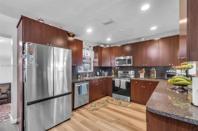 a kitchen with kitchen island granite countertop stainless steel appliances and wooden cabinets