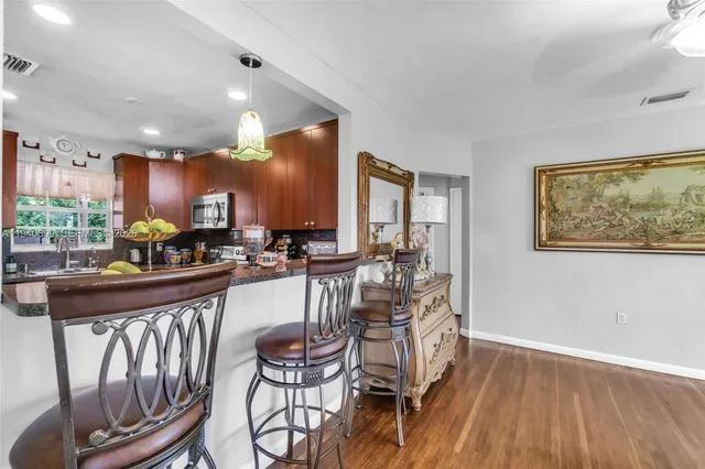 a kitchen with stainless steel appliances kitchen island granite countertop a table chairs and a refrigerator
