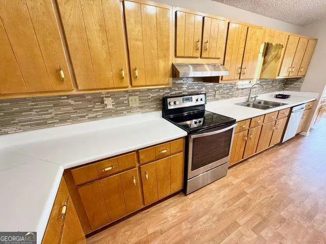 a kitchen with stainless steel appliances granite countertop a stove a sink and a microwave