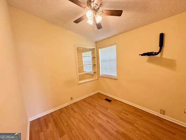 a view of a room with wooden floor and a ceiling fan