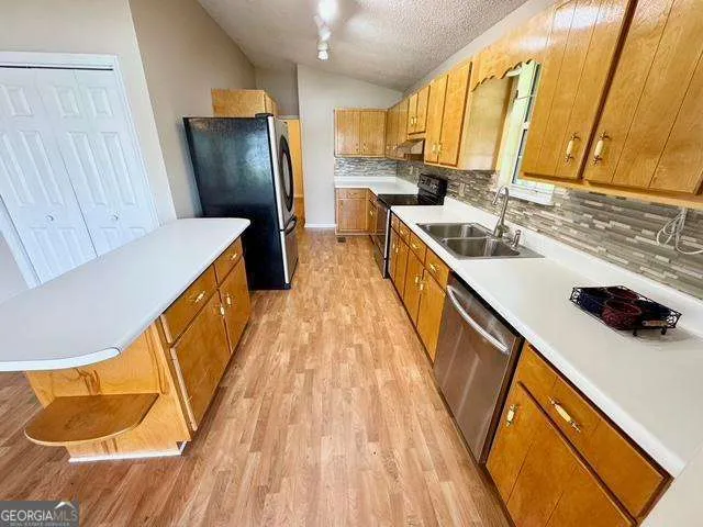 a kitchen with a sink a refrigerator and wooden floor