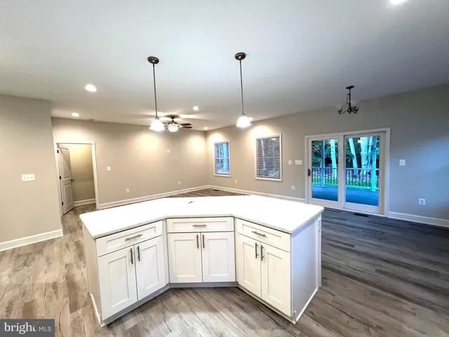 a kitchen with stainless steel appliances kitchen island granite countertop a sink a stove a refrigerator and island with wooden floor