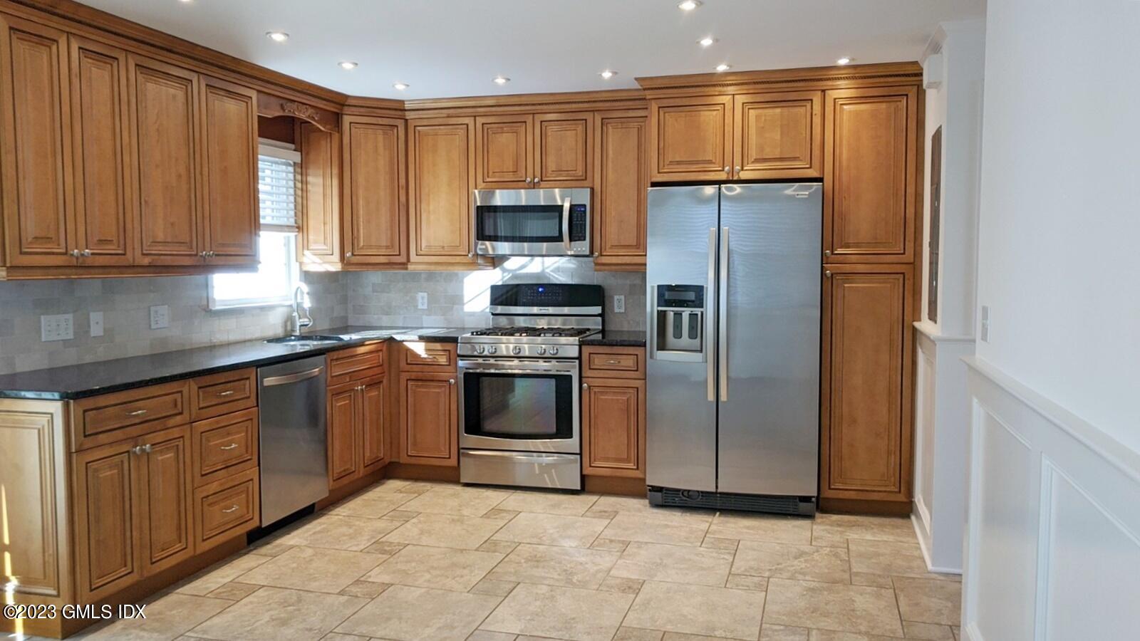 66 Ute Place, Unit A Greenwich, CT 06830 - Photo 3 of 18 a kitchen with kitchen island granite countertop wooden cabinets stainless steel appliances and a window
