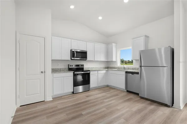 a kitchen with a refrigerator stove and white cabinets