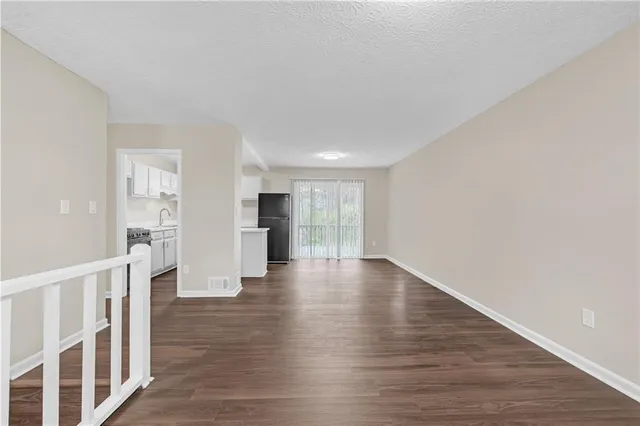 a view of an empty room with wooden floor and a large window