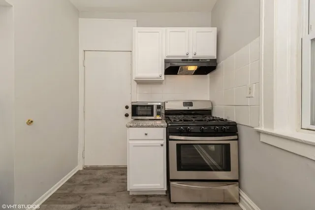 a kitchen with granite countertop white cabinets and a stove top oven