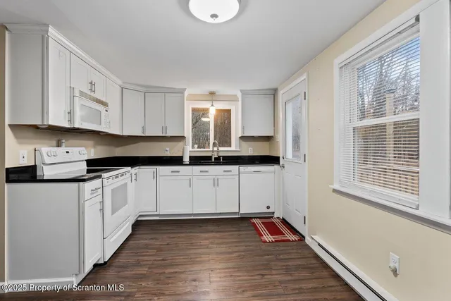 a kitchen with granite countertop a stove and white cabinets