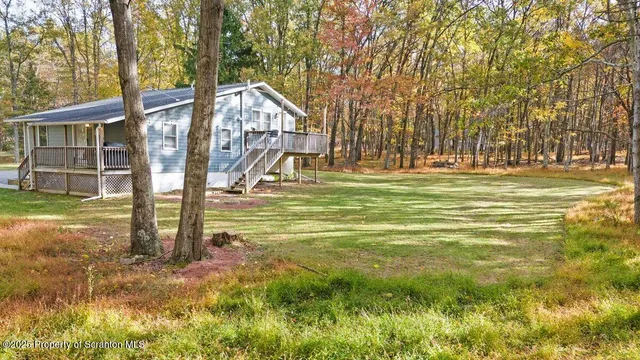 a view of a house with a big yard and large trees