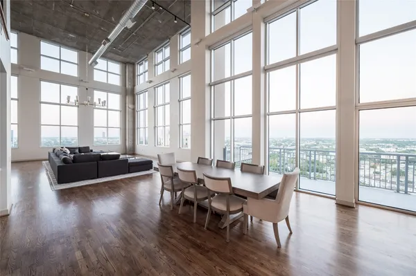 a dining room with wooden floor and large windows