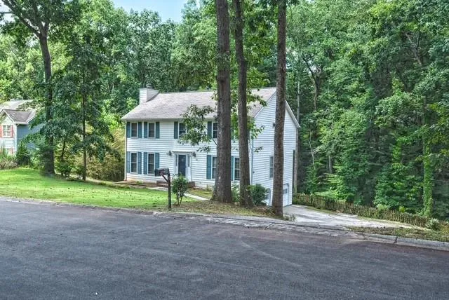 a view of a house with a yard and large trees