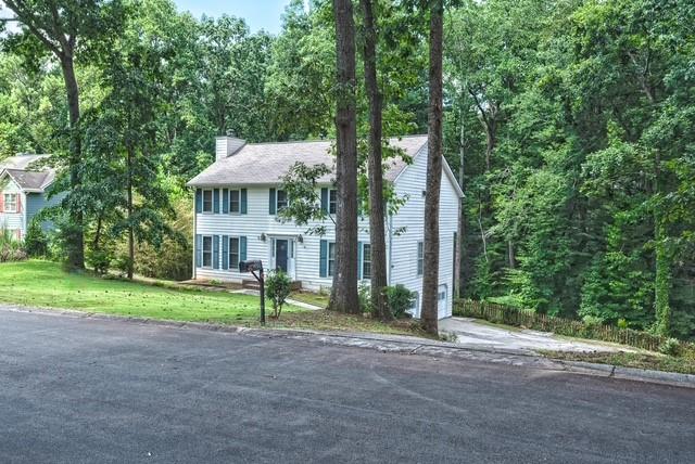 a view of a house with a yard and large trees