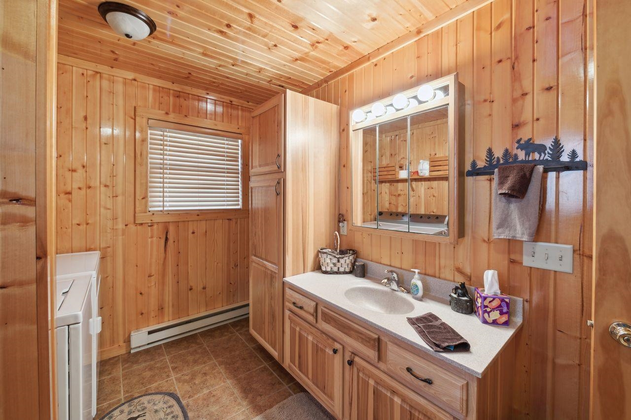 28255 Friendly Valley Road Washburn, WI 54891 - Photo 12 of 34 Bathroom featuring wooden ceiling, a baseboard heating unit, wood walls, washer and clothes dryer, and vanity