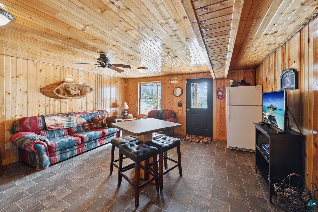 28255 Friendly Valley Road Washburn, WI 54891 - Photo 14 of 34 Dining room with ceiling fan, wooden ceiling, and wood walls