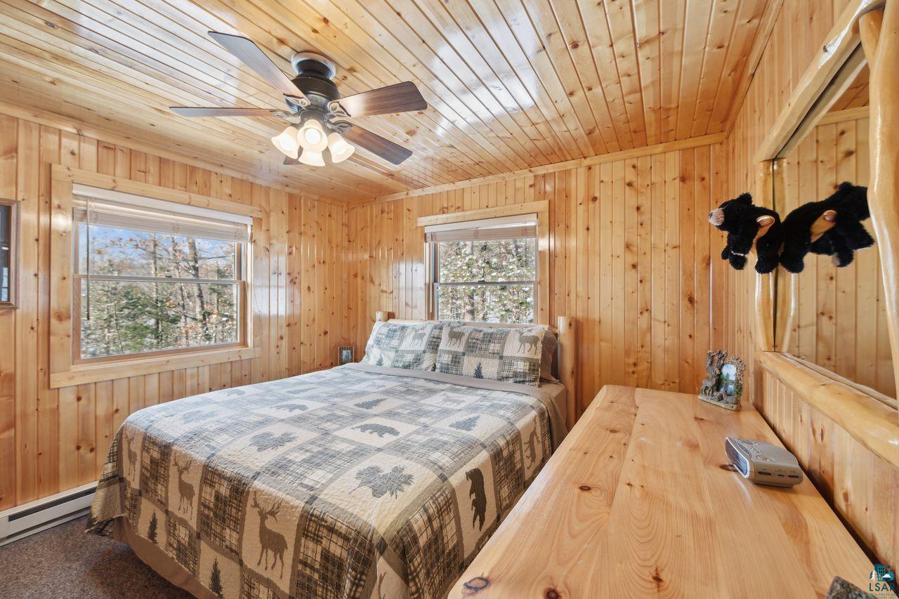28255 Friendly Valley Road Washburn, WI 54891 - Photo 9 of 34 Carpeted bedroom with ceiling fan, wooden walls, wood ceiling, and a baseboard radiator