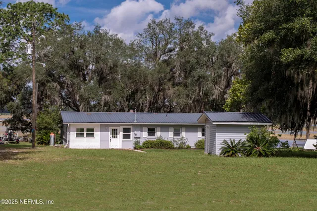 aerial view of a house next to a big yard and large trees