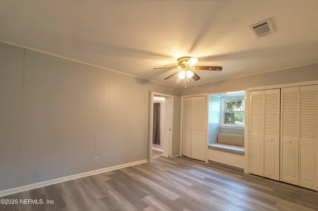 an empty room with wooden floor and chandelier fan