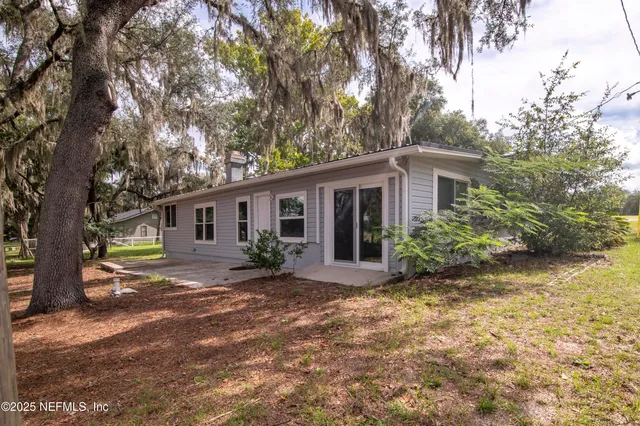 a view of a yard in front of a house with large tree