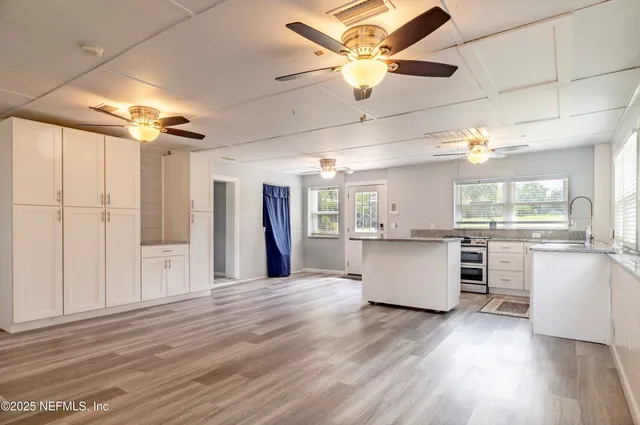 a kitchen with stainless steel appliances kitchen island hardwood floor and a window