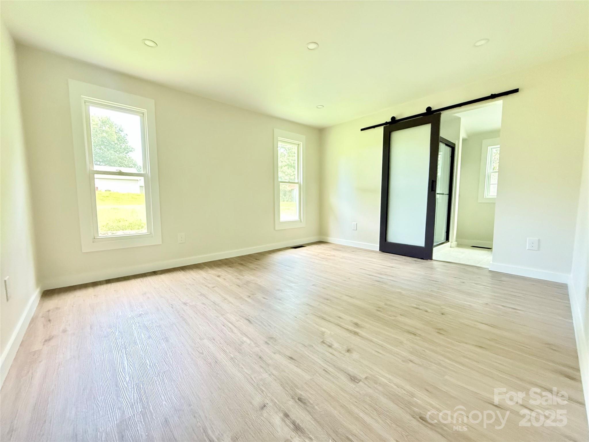 668 Union Cemetery Road Southwest Concord, NC 28027 - Photo 11 of 24 an empty room with wooden floor and windows