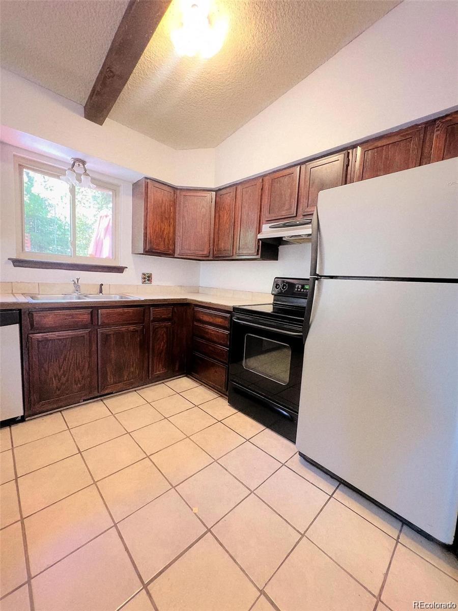 19424 Silver Ranch Road Conifer, CO 80433 - Photo 7 of 17 a kitchen with a sink a stove top oven and white cabinets