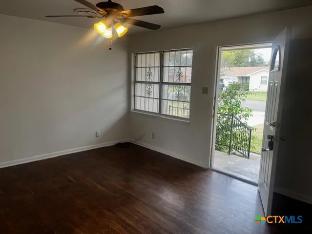 an empty room with wooden floor and windows