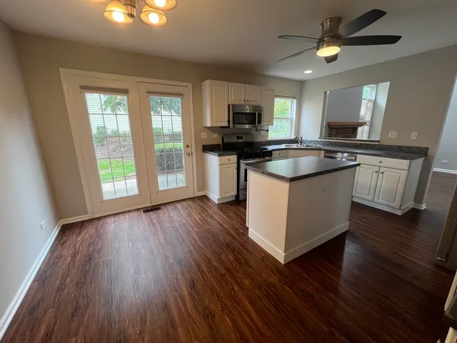 a kitchen with stainless steel appliances granite countertop wooden floors and white walls