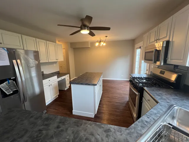 a kitchen with stainless steel appliances a stove a refrigerator a sink a oven with wooden floor and cabinets