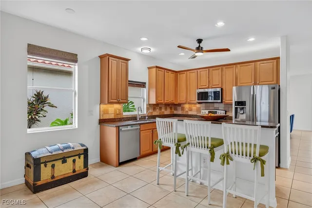 a kitchen with stainless steel appliances kitchen island granite countertop a refrigerator a stove top oven and a sink