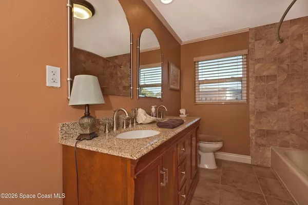 a bathroom with a granite countertop toilet a sink and a mirror