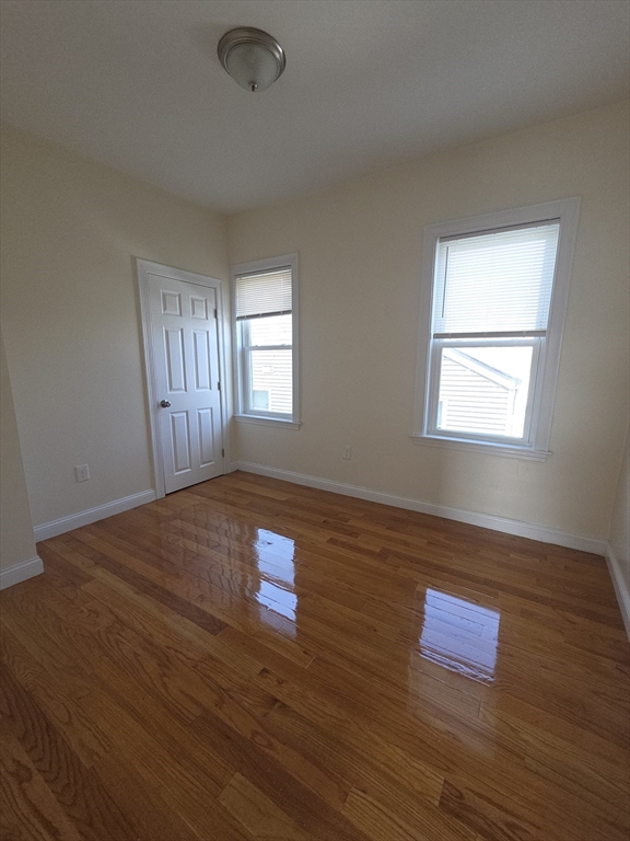 92 Lucerne Street, Unit 2 Boston, MA 02124 - Photo 2 of 7 an empty room with wooden floor and windows