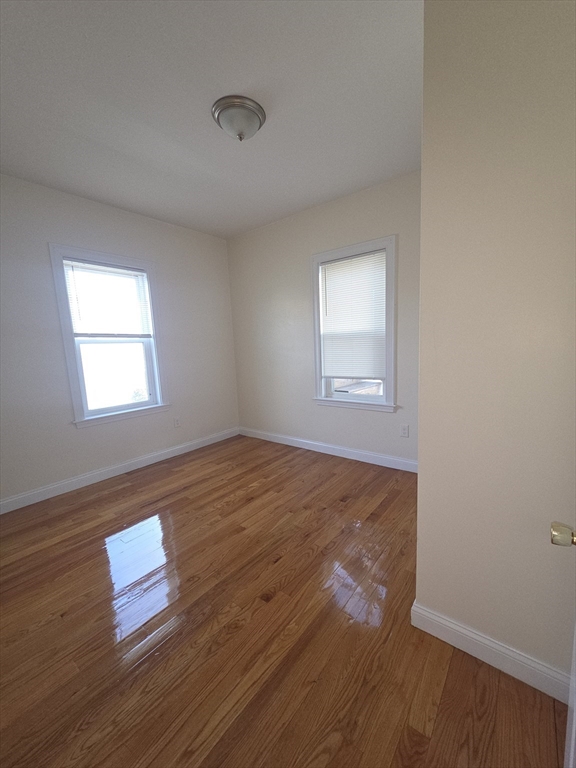 92 Lucerne Street, Unit 2 Boston, MA 02124 - Photo 5 of 7 an empty room with wooden floor and windows