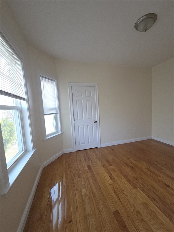 92 Lucerne Street, Unit 2 Boston, MA 02124 - Photo 6 of 7 a view of an empty room with wooden floor and a window