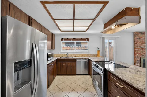 a large kitchen with stainless steel appliances granite countertop a large counter top a stove and a wooden floors