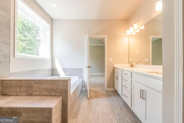 a spacious bathroom with a double vanity sink a mirror and a bathtub