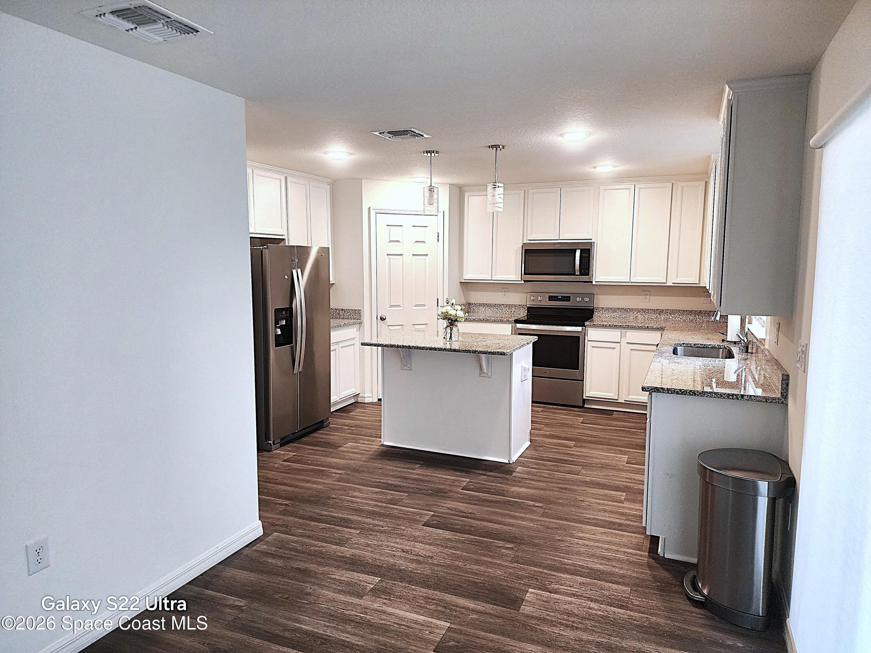 1043 Corbin Circle Southwest Palm Bay, FL 32908 - Photo 6 of 18 a kitchen with stainless steel appliances granite countertop a stove top oven a sink and a refrigerator