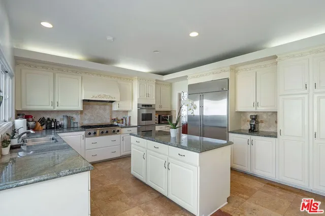 a kitchen with granite countertop a sink stainless steel appliances and white cabinets