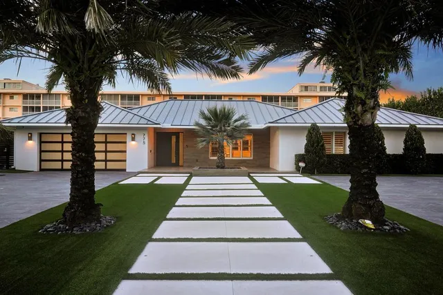 a front view of a house with a garden and trees
