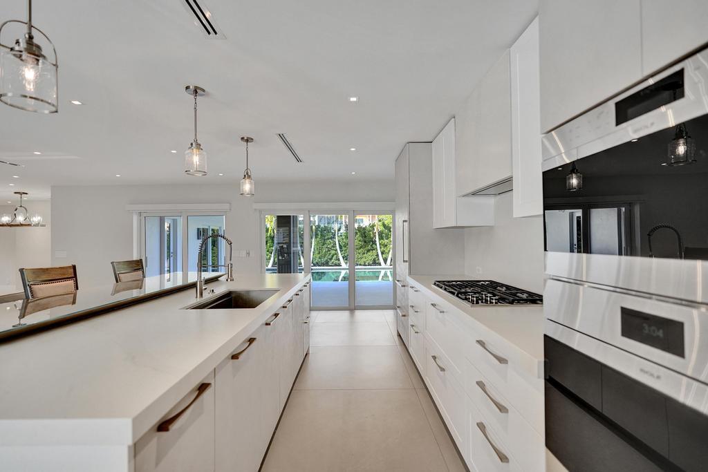 775 Northeast 39th Street Boca Raton, FL 33431 - Photo 27 of 88 a kitchen with stainless steel appliances a stove a sink a microwave a stove and white cabinets