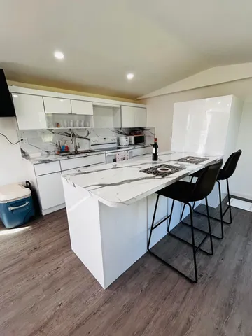 a kitchen with stainless steel appliances a dining table chairs a sink and a stove