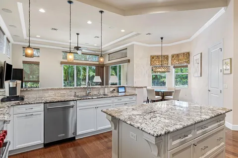 a kitchen with stainless steel appliances granite countertop stove top oven a sink dishwasher and white cabinets with wooden floor