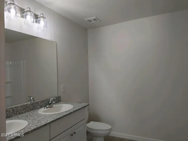 a bathroom with a granite countertop sink a toilet and mirror