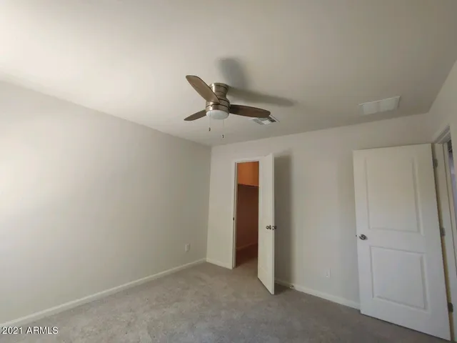 an empty room with closet and ceiling fan