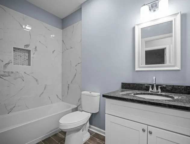 a bathroom with a granite countertop toilet a sink and a bathtub