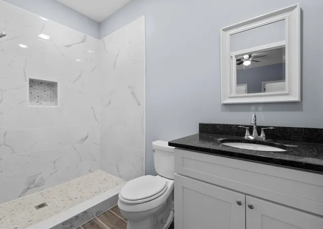 a bathroom with a granite countertop sink a toilet and a mirror