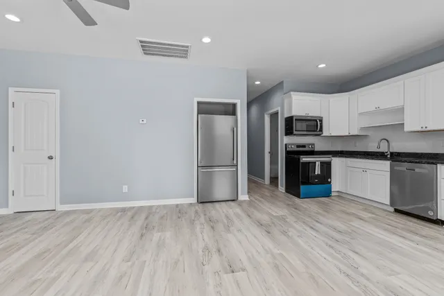 a kitchen with stainless steel appliances granite countertop a stove top oven a sink and dishwasher with wooden floor