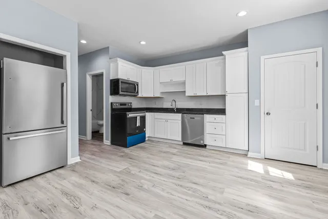 a kitchen with granite countertop a refrigerator and a stove top oven